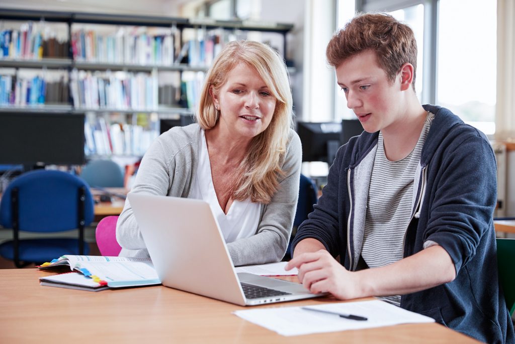 Uma imagem contendo uma mulher e um homem, com um computador sob a mesa, estudando inglês para iniciantes